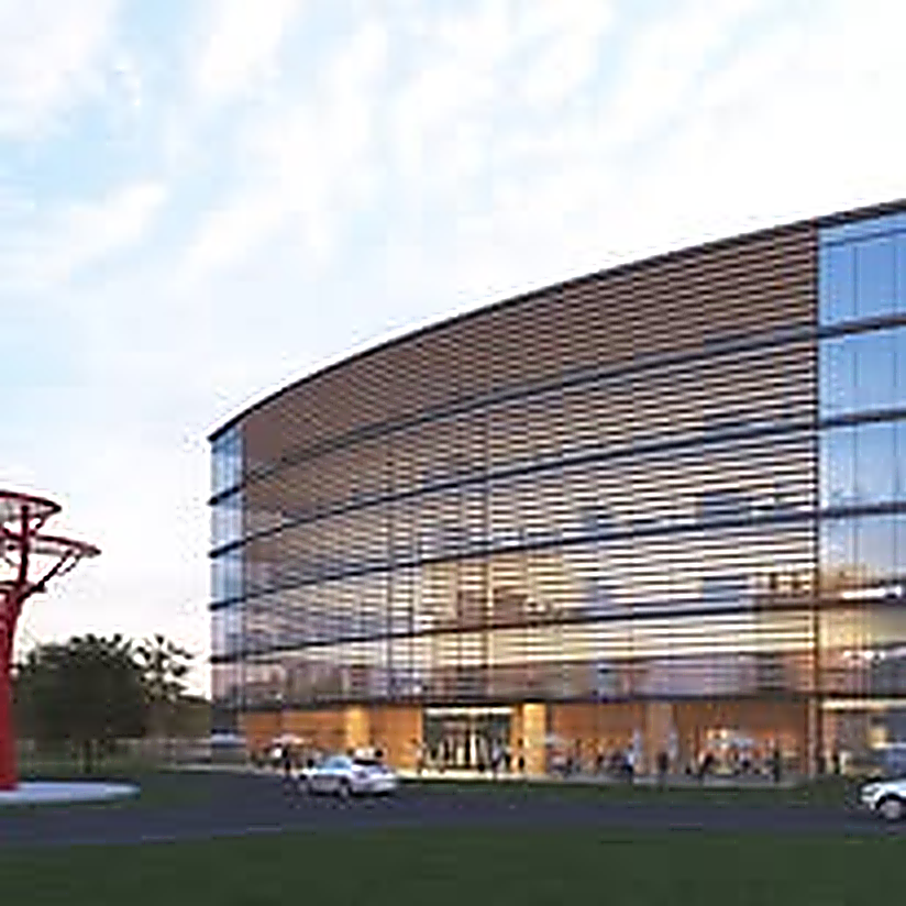 Curved glass office building with wood louvers at sunset