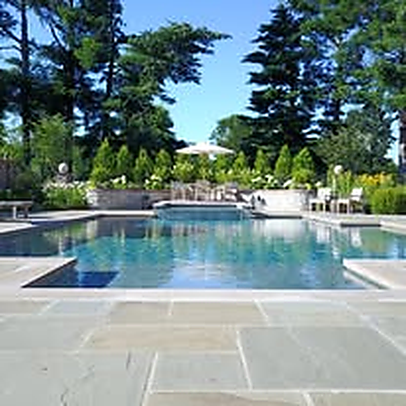 Manicured resort pool surrounded by evergreens and bluestone terrace