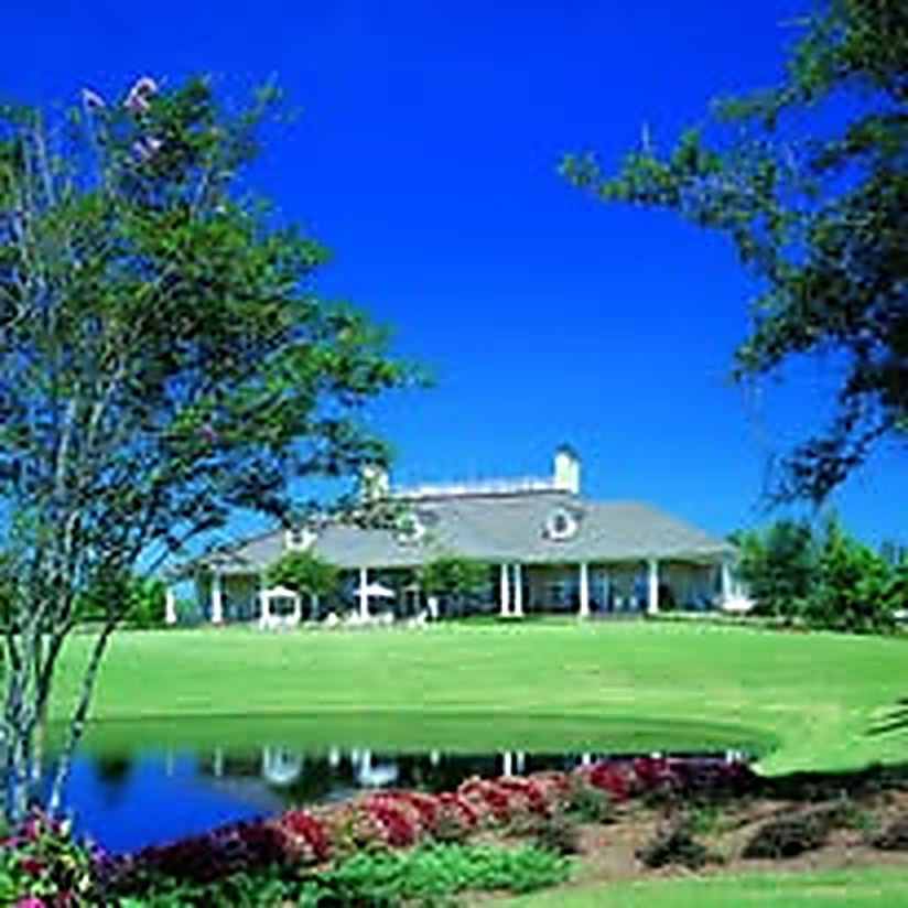 Southern-style resort clubhouse with wraparound porch overlooking a landscaped pond