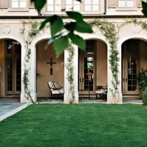 Arched loggia with vine-covered columns and courtyard lawn